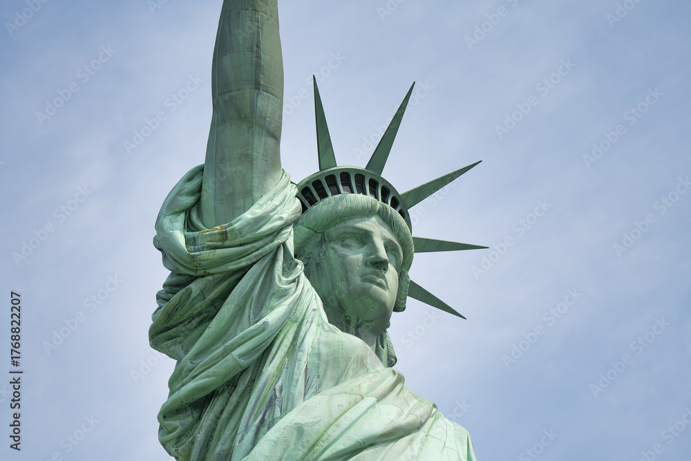 Fototapeta premium Close-up frontal perspective of Liberty Enlightening the World monument with harbor background