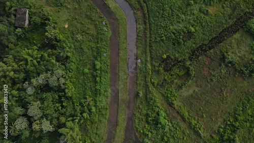 Fotografie Road through lush green hillside landscape