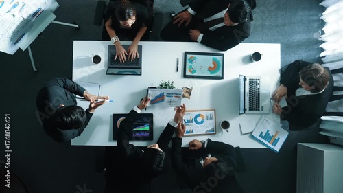 Top down aerial view of manager standing and present marketing plan to skilled investor. Diverse business team working together to analyze financial statistic graph at meeting table. Directorate.