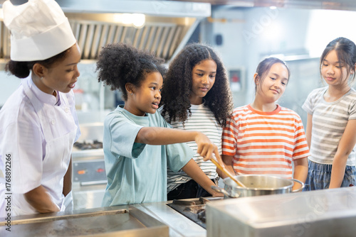 Photos Professional female chef teaching diverse group of kids how to cook in modern kitchen