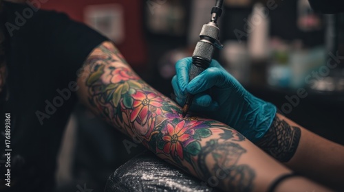 A tattoo artist in a tattoo parlor, using a tattoo machine to tattoo a colorful flower on a person's arm.