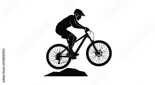 Dynamic silhouette of a mountain biker performing a jump over an obstacle on a trail