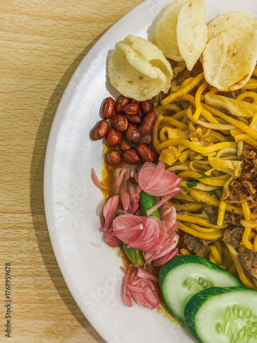 Wallpaper Mural A plate of traditional Indonesian Mie Aceh served with rich spicy curry sauce, beef, cucumber slices, peanuts, crackers, and fried shallots on top. Torontodigital.ca