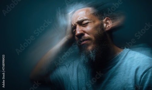 Man experiencing headache, holding head, blurred effect, suffering, pain, stress.