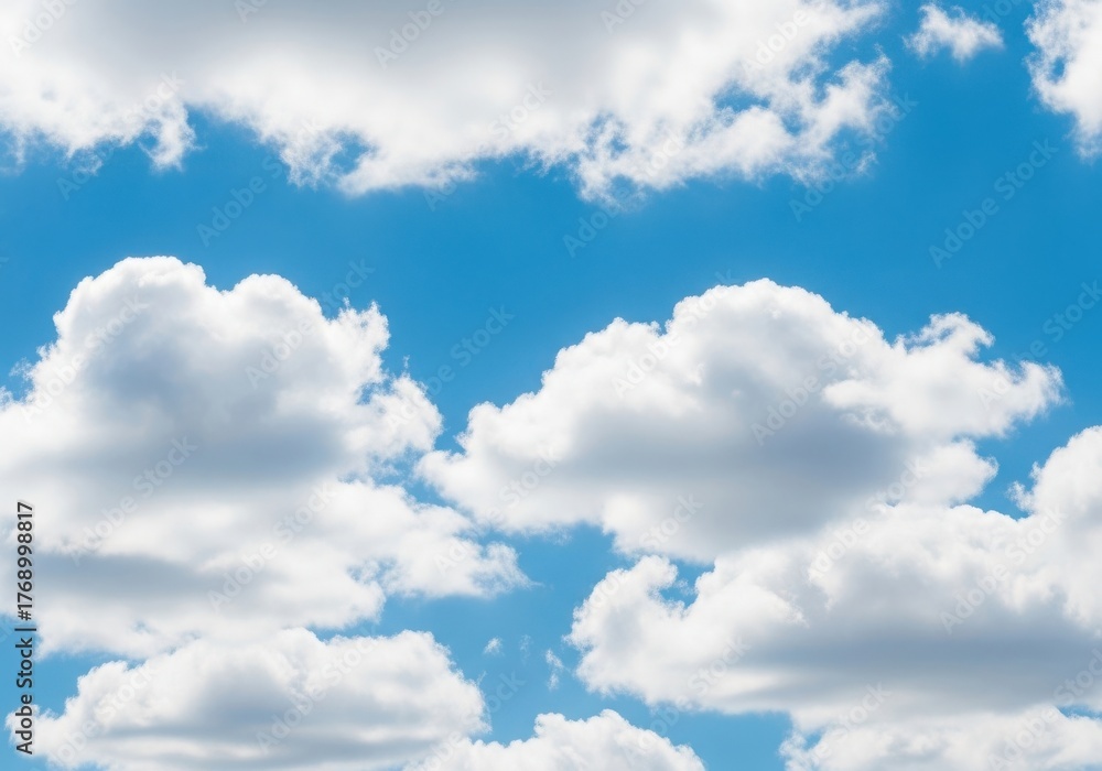 Fototapeta premium Fluffy white cumulus clouds floating in a clear blue sky on a sunny day