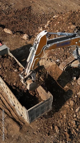 Excavator loading dump truck with soil on construction site. Clip