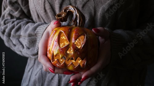 Cozy autumn scene featuring woman holding glowing halloween pumpkin with knit sweater
