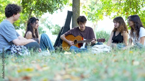 group of young people playing guitar at park