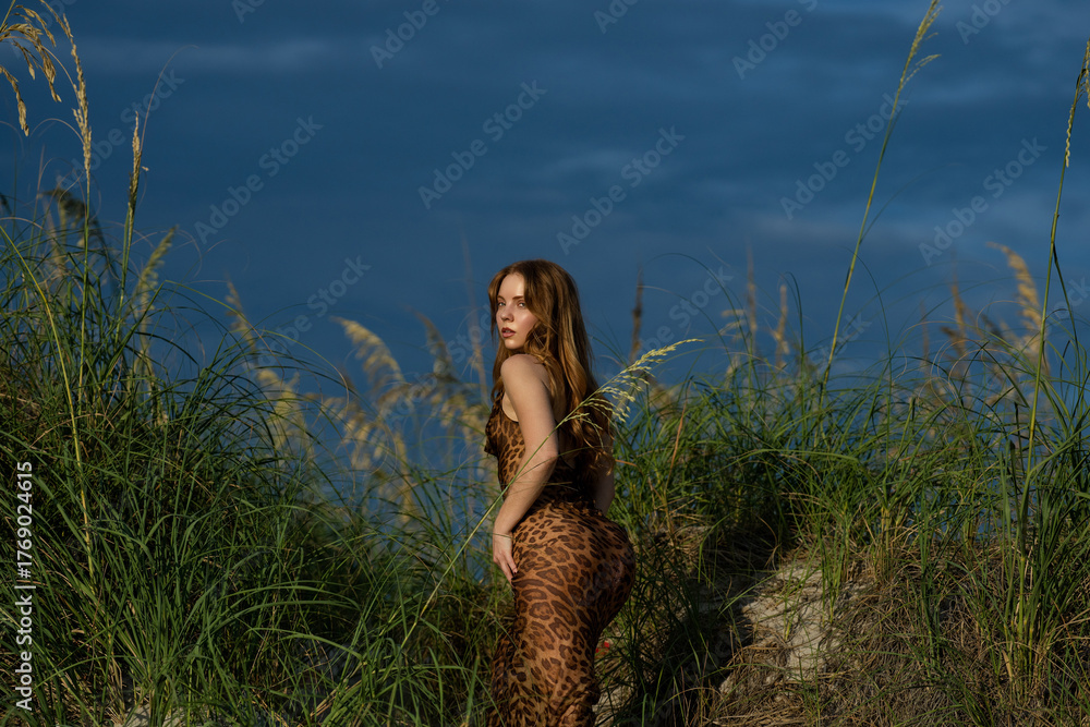 Obraz premium Sensual romantic woman in a long dress in nature. Portrait of a beautiful young woman posing in fashion dress on nature. Attractive booty model girl. Dreaming romantic woman in leopard dress.