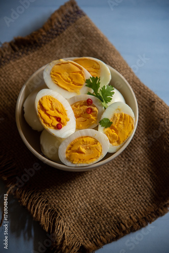 Sliced boiled eggs in a bowl with parsley leaves. Top view, selective focus.