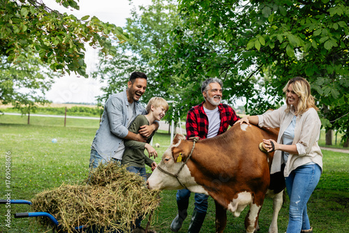 Fotografie Multi generational family bonding with a farm cow