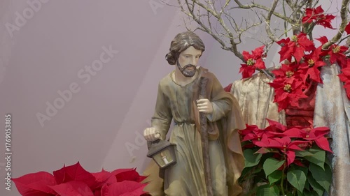Catholic nativity scene with saint Joseph. Christmas religious still life with red flowers prayer and faith detail closeup