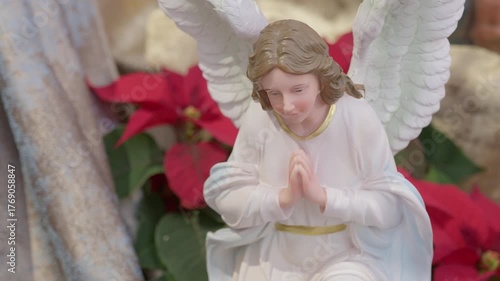 Catholic nativity scene with angels. Christmas religious still life with red flowers prayer and faith detail closeup