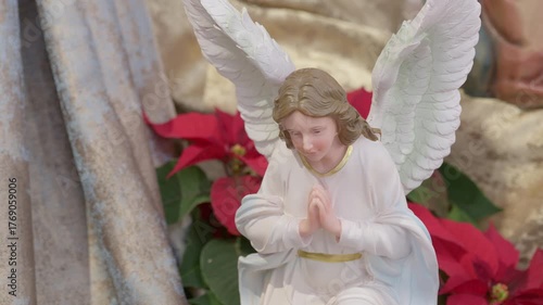 Catholic nativity scene with angels. Christmas religious still life with red flowers prayer and faith detail closeup