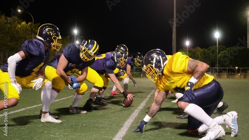 American football players practicing a scrimmage during a night training session