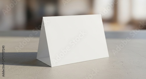 Blank triangular table tent on smooth surface in bright sunlit room