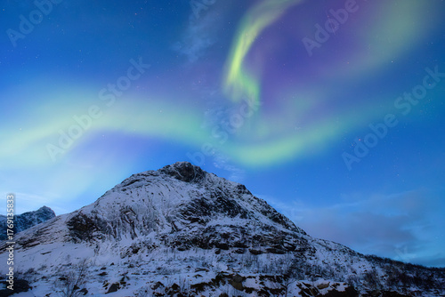 Aurora Borealis. Northern lights and starry sky. Nature on the north. Scandinavian countries. Snow and ice on the mountains. Landscape in winter time. Background, wallpaper, postcard.