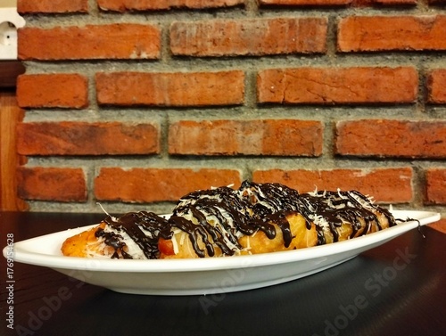 fried bananas with chocolate and cheese topping on a leaf-shaped plate