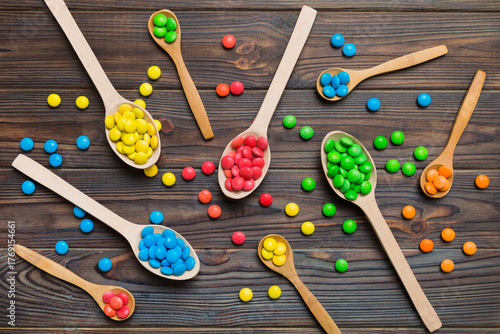delicious colorful sweet candies on spoon on colored background . Confectionery decor top view with copy space