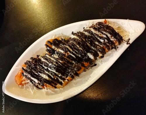 fried bananas with chocolate and cheese topping on a leaf-shaped plate