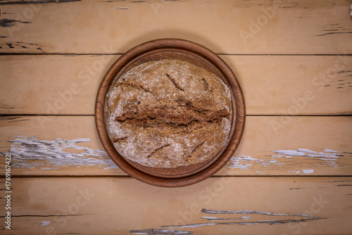 Top view of sourdough walnut bread on round board on aged beige table
