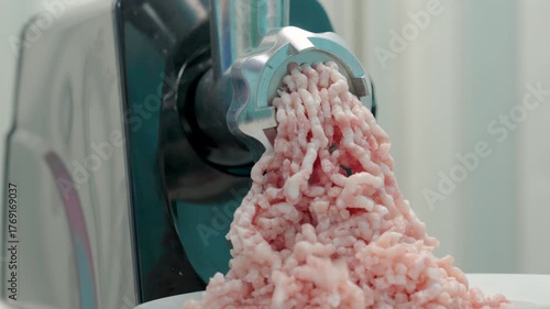 An electric meat grinder grinds pork.