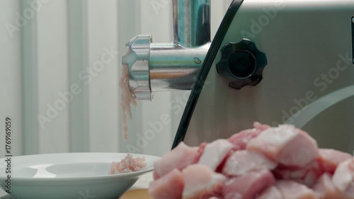 An electric meat grinder grinds pork.