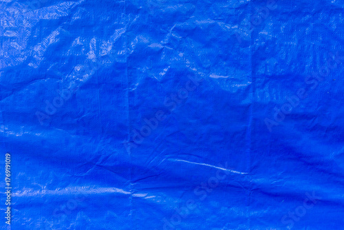 The bright blue plastic awning is shiny in places in the sun. The texture and grain are visible.