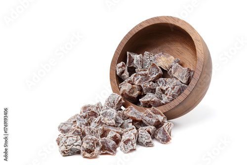 Dried salted plums are being poured from a wooden bowl. isolated on white background.