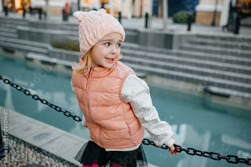 Young girl enjoys playful moment by the water in a charming outdoor setting during winter