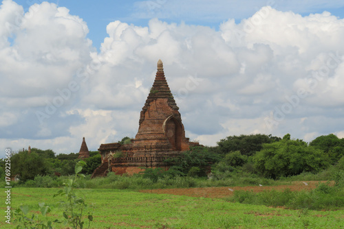 A Buddhist Pagoda surrounded by green fields in Bagan, Myanmar