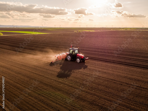 Farming tractor seeding field during sunset aerial view