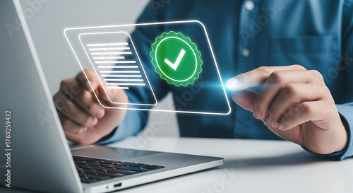 Person using a laptop and touching a digital screen displaying document and verification check mark icons, representing compliance and approval.