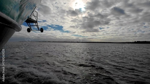 A tranquil boat ride unfolds, showcasing serene waters and breathtaking cloud formations stretching across the horizon