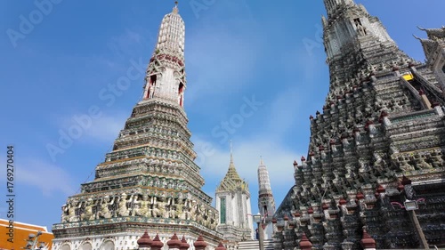 BANGKOK, THAILAND - 6th OCTOBER 2024: Camera rises from behind lilies to reveal Thonburi Pagoda of Wat Arun in Bangkok Thailand on a sunny morning