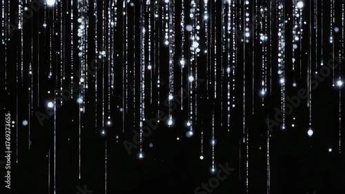 A continuous loop animation featuring sparkling, white, shimmering particles and light trails falling like rain or a curtain against a dark, black background