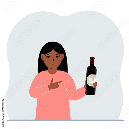 A little girl holds a bottle of wine in her hand. The concept of alcohol abuse, alcohol addiction by minors.