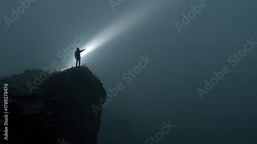 Person on a cliff shining a light into the darkness, searching for something