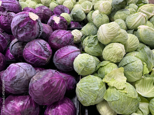 Fresh green and purple cabbages neatly stacked in a grocery store