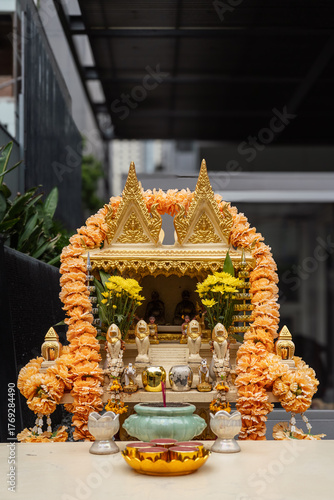 Gold Thai Spirit House with Offerings and Marigold Garlands in Bangkok, Thailand