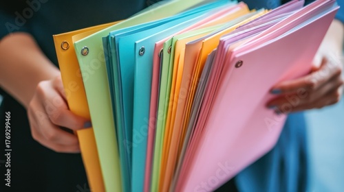 Organized with Flair: Woman Holding a Vibrant Array of Ring Binder Files
