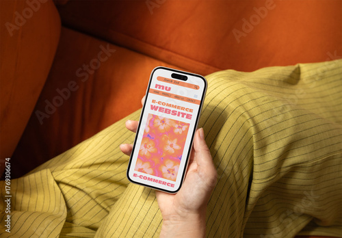 A hand holding a smartphone while sitting on a cozy couch