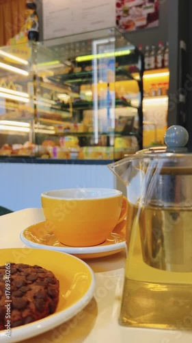 A yellow teacup and transparent teapot with tea on table in cafe. Vertical video. Blurred background. High quality 4k footage