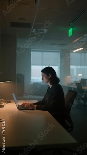 Woman Working on Laptop in Modern Office at night. Typing on a laptop.
