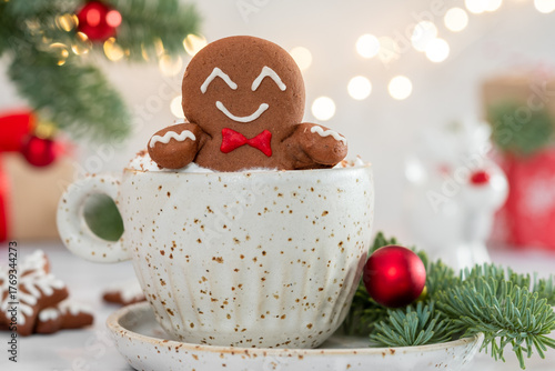 A gingerbread man is sitting in a cup of hot chocolate