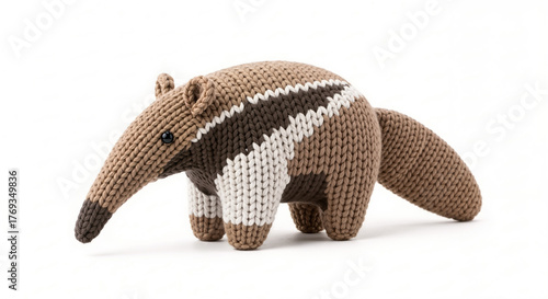 A stuffed, knitted anteater toy with a long snout and a distinctive brown, white, and tan striped pattern across its body.