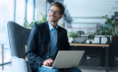 Businessman using laptop computer in office. Happy man, entrepreneur, small business owner working online.