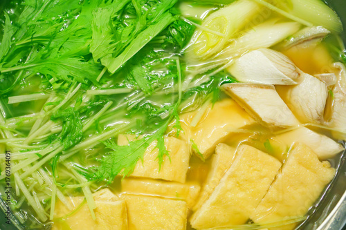 A stewed hot pot dish featuring mizuna greens, green onions, mackerel, and fried tofu—a Japanese winter delicacy.