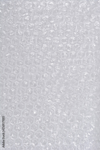 A vertical, full-frame macro shot of clear plastic bubble wrap, creating a repetitive texture of inflated air pockets