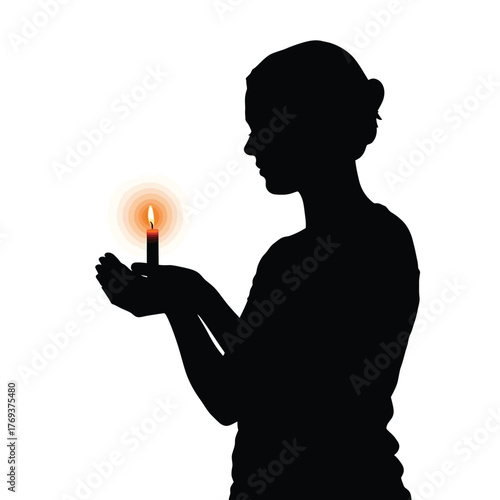 Silhouette of a person holding a glowing candle in their hands